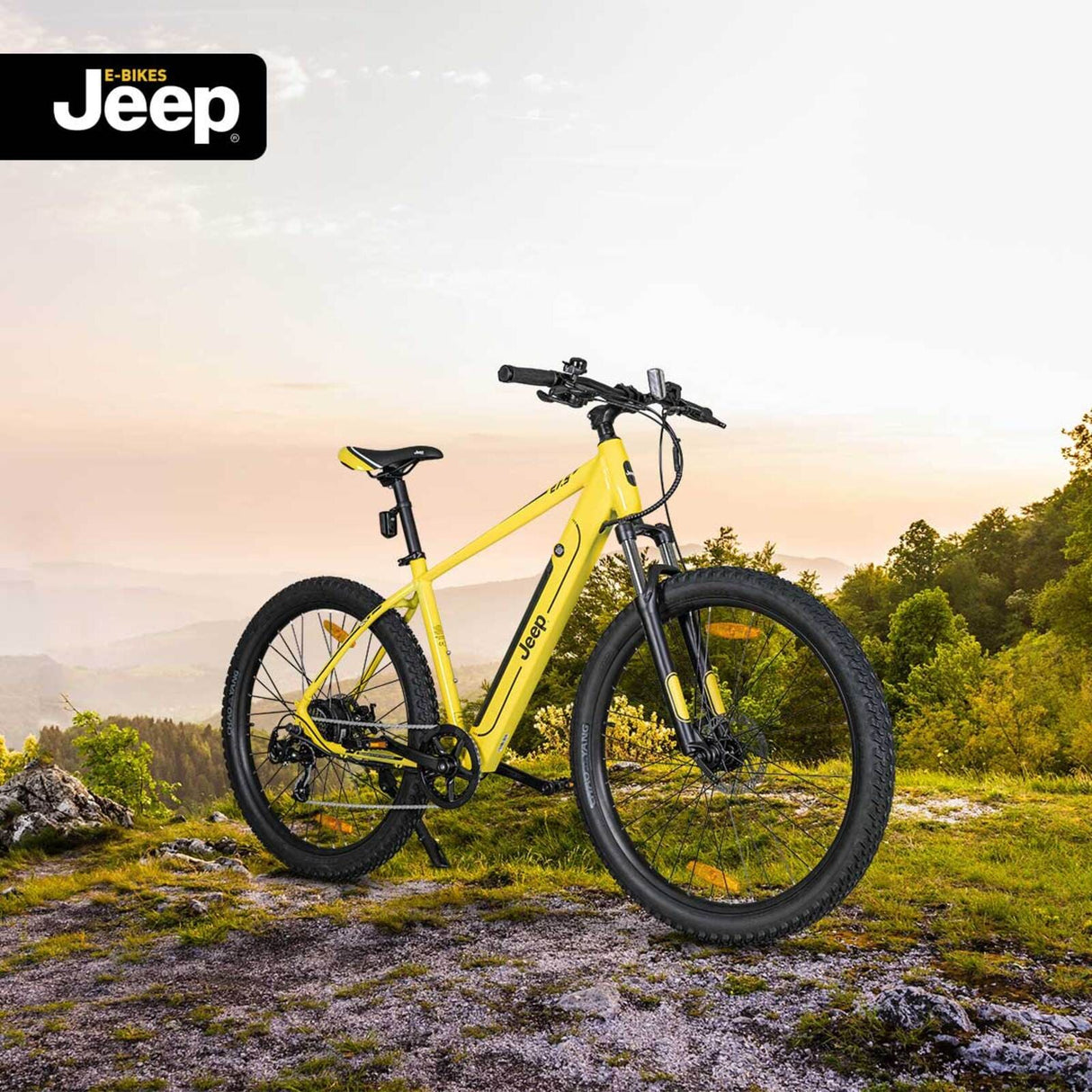 Gelbes Jeep Mountain E-Bike auf einem Waldweg in bergiger Outdoor-Landschaft