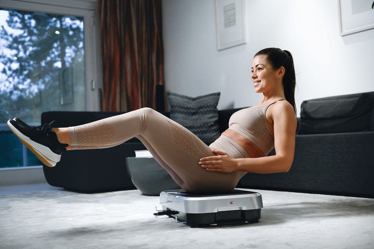 Vibrationsplatte für Fitness und Training zu Hause mit Frau bei einer Bauchübung
