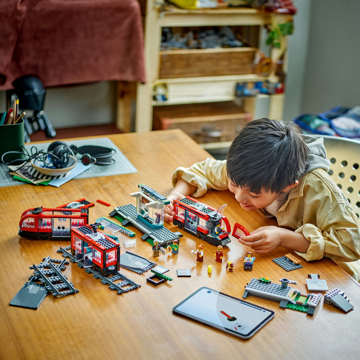 Kind baut LEGO City 60423 Straßenbahn mit Haltestelle und Schienen auf einem Tisch