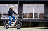 Mann fährt ein kompaktes E-Bike mit breiten Reifen in urbaner Umgebung